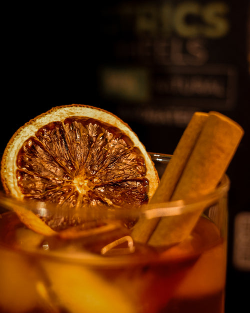 Cocktail garnished with cinnamon quill and blood orange slice